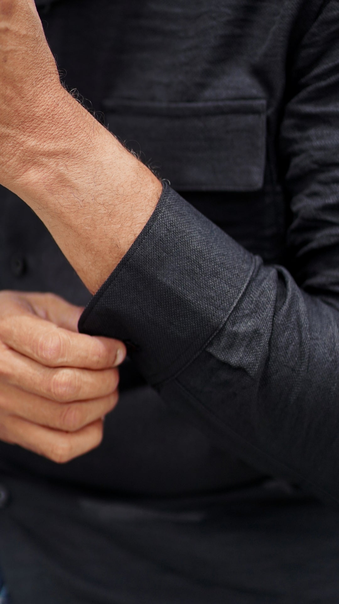 Image contains a zoomed click of black double-pocket, full-sleeve shirt from Mod Maven, Emphasizing on the shirt cuff.
