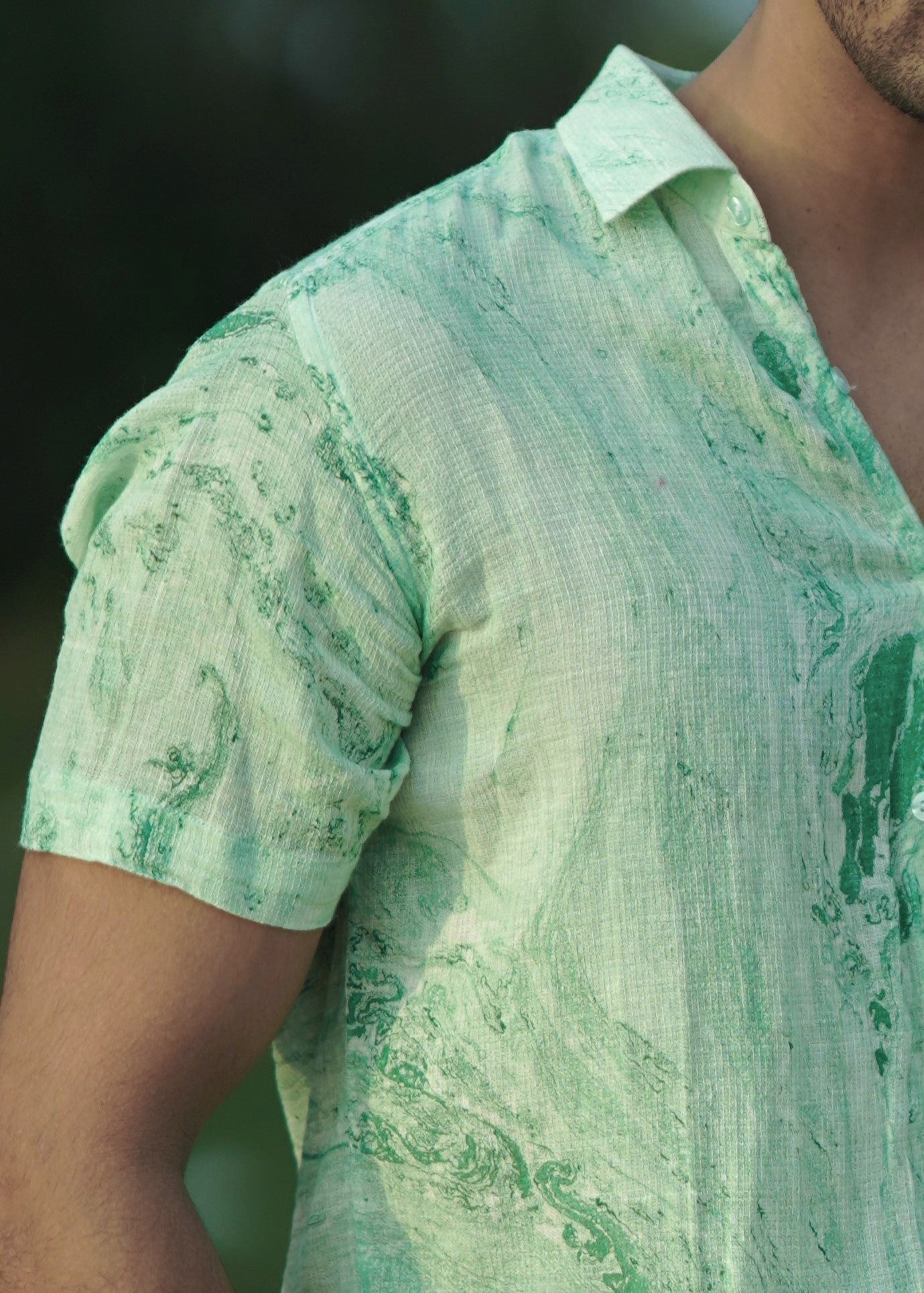 Close up shot of the model wearing a stylish Dobby cotton marble printed half-sleeve shirt in shades of green from the Mod Maven brand. Image focuses on the shirt providing a detailed view of the fabric texture.