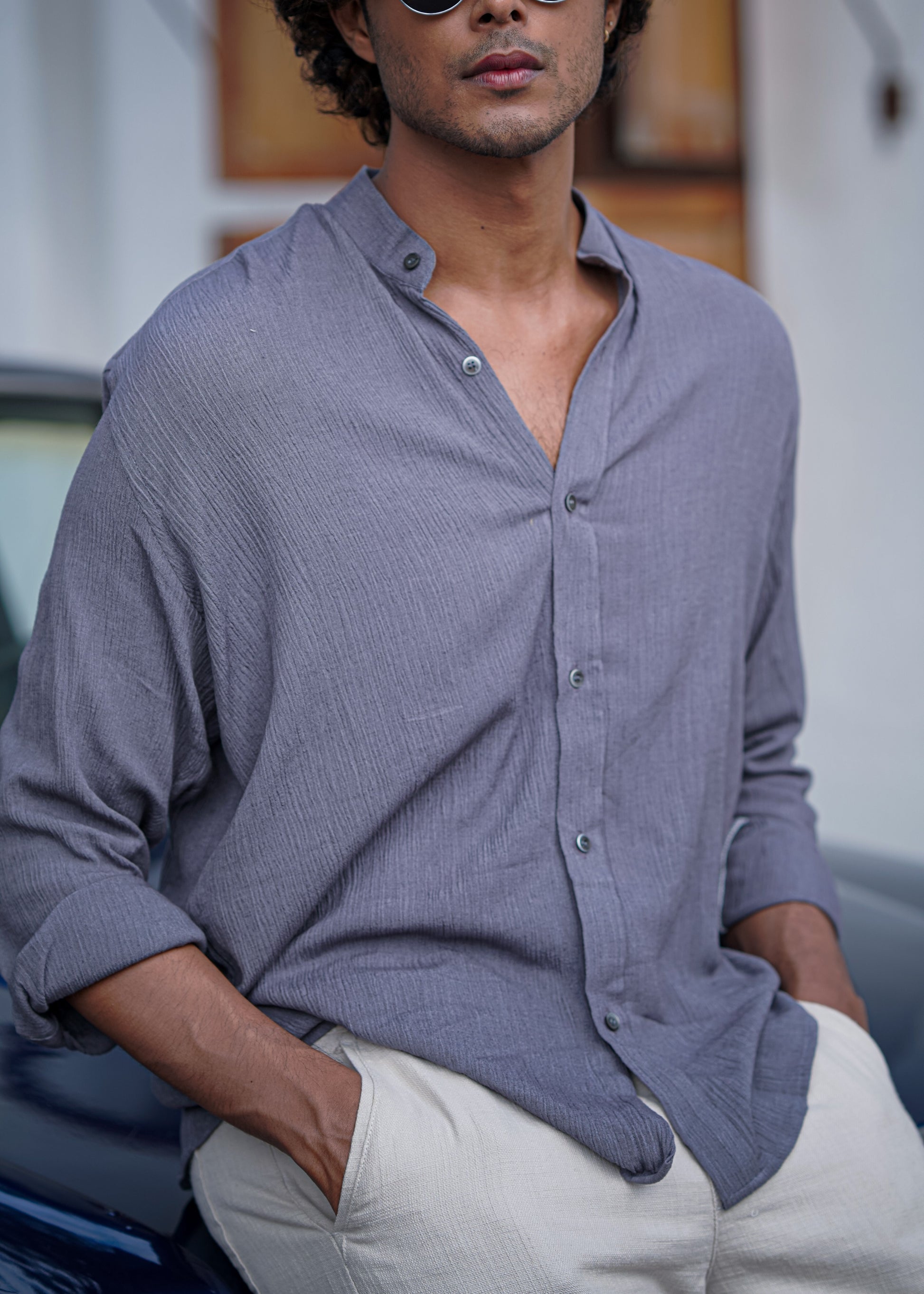 Close up view of Mod Maven Lilac Grey Crushed Cotton Full Sleeve Shirt paired with Off-White Comfortable Fit Pants. Model sitting on a vintage dark blue car.